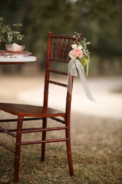 Chiavari chair with floral treatment under the oaks at a private venue.