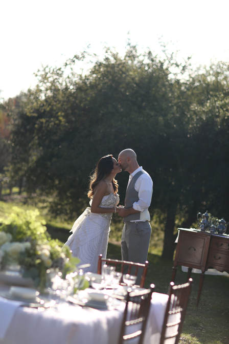 Bride and groom kissing by oak trees.