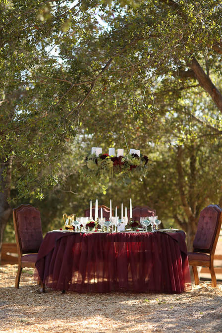 Marsala wedding table under a floral chandelier.